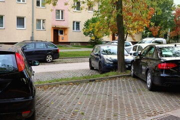 Parking lot with parked cars belonging to a housing estate with old apartment blocks