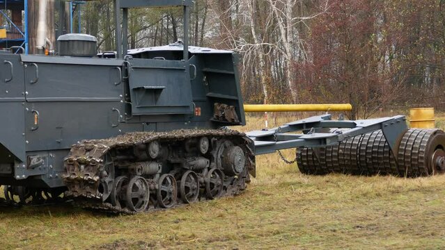 A demining vehicle is driving across a field. A heavy shaft presses against the ground. The concept of humanitarian demining.