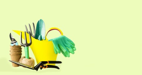 Banner on a light table background - gardening tools: trowel, rake, green watering can, gloves,...