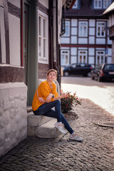 Fototapeta na wymiar Reflective Young Woman Sitting on Steps in Quaint European Street