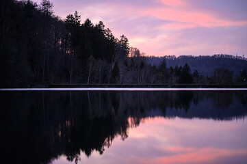 Dusk Colors Reflecting on Lake Surface with a Silhouette of Trees and Hills