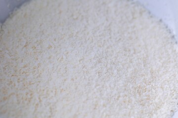 A portrait of white coconut powder or coco grounds in a white bowl ready to be used in the kitchen by a baker to use in delicious coockies