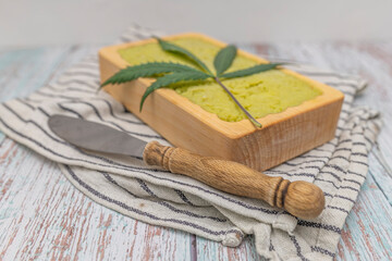 Striped dish towel with yellow marijuana butter in wooden case and knife