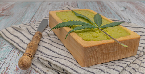 Striped dish towel with yellow marijuana butter in wooden case and knife