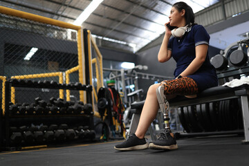 Sport Disable woman with prophetic leg using a smartphone to communicate with her friend at the gym after workouts