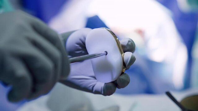 Doctor uses the screw driver in the knee prosthetic. Close up. Preparation for the orthopedic procedure.