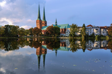 Lubeck, Germany. View of Lubeck Cathedral from the opposite shore of Muhlenteich (Mill pond) in autumn evening. The cathedral was started in 1173 and consecrated in 1247. - 737499042