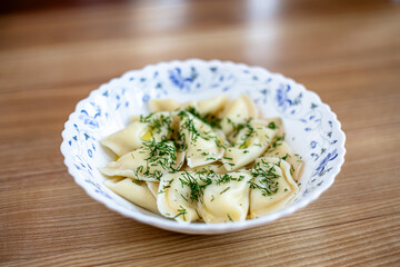 Dumplings sprinkled with dill are in a plate