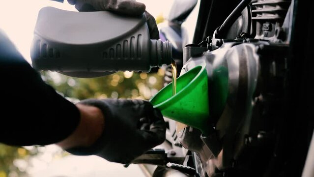 changing the oil in a motorcycle, pouring new engine oil into a motorcycle