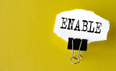 ENABLE- the word is printed on a white piece of paper on a yellow background