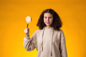 Smiling girl holding magnifier in hand. Education and curiosity concept