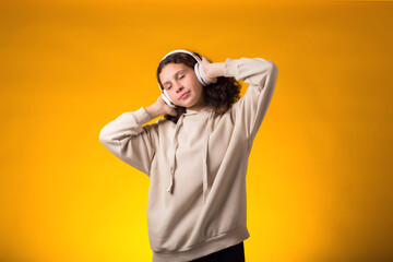 Smiling girl enjoying music in headphones on yellow background. Lifestyle and leasure concept