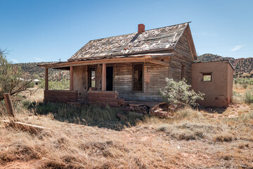 Abandoned homestead house in the arid red sand desert landscape of New Mexico near old Historic...