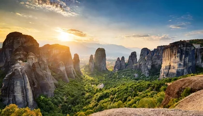 Fotobehang panoramic landscape of meteora greece at romantic sundown time with real sun and sunset sky meteora incredible sandstone rock formations the meteora area is on unesco world heritage © Dayami