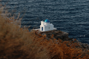 The Church of Epta Martyres on Sifnos perches on a rocky cliff above the Aegean Sea. Its white...