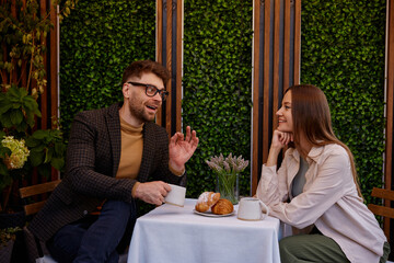 Young man and woman coworkers talking in cafe enjoying relax time