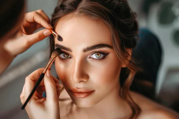 Fototapeten A makeup artist is applying eyeshadow on a young beautiful woman © piai