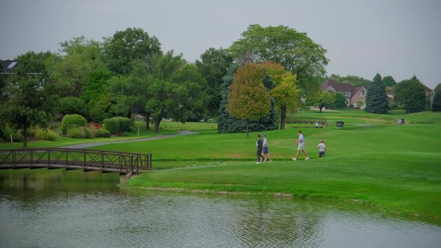 People on golf course amidst water, natural landscape. Wide shot