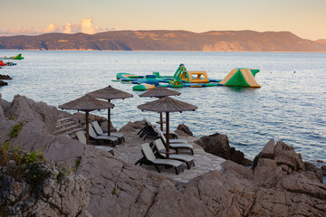 Straw beach umbrellas on the beach of Rabac, Croatia - 737528495