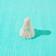Shuttlecock with shadow on turquoise blue crepe paper. Minimal badminton concept.