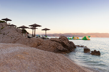 Straw beach umbrellas on the beach of Rabac, Croatia