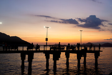 Unidentifiable tourists, admiring the sunset, on the fishermen's deck, in Santos, Ponta da Praia