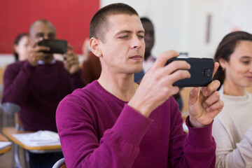 Fototapeta premium Multinational students with smartphones at business school doing videos of session