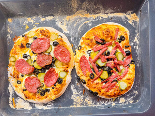 Two homemade pizzas with different toppings on a wooden board.