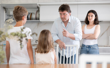 Father and mother telling off their son and daughter for disobedience