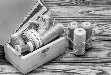 sewing threads on spools in a wooden box black and white background