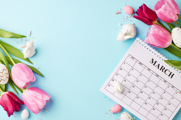 Tulip time: Easter's gentle reminder. Top view photo of pink tulips, March calendar, white bunny figures and speckled eggs on a pastel blue backdrop for gentle nudge of the spring holiday ahead