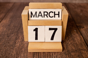 March 17 calendar date text on wooden blocks with blurred park background. Copy space and calendar...