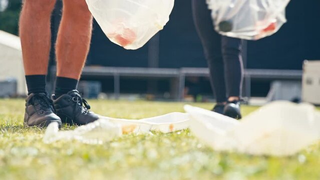 Close Up Of Volunteers Picking Up Litter After Outdoor Event Like Concert Or Music Festival