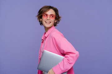 Obraz premium Portrait of beautiful smiling woman using laptop wearing stylish pink clothes holding laptop