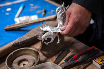 Craftsman works silver to obtain an ornament