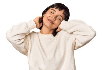 Young Hispanic woman with short black hair in studio feeling confident, with hands behind the head.