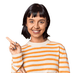 Young Hispanic woman with short black hair in studio smiling cheerfully pointing with forefinger away.