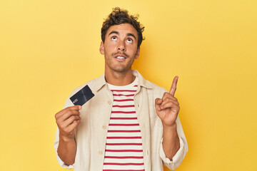 Man holding credit card on yellow having some great idea, concept of creativity.