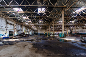 Abandoned factory. Large empty ruined industrial hall with broken remnants of equipment