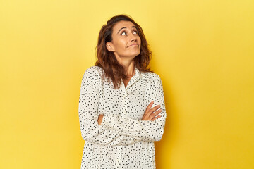 Middle-aged woman on a yellow backdrop dreaming of achieving goals and purposes