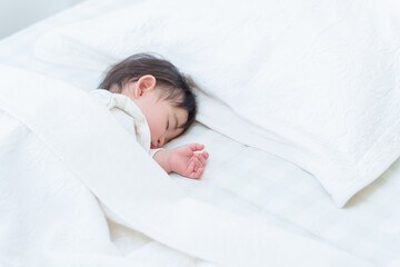Fototapeta na wymiar ベッドでお昼寝する赤ちゃん