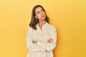 Middle-aged caucasian woman on yellow tired of a repetitive task.