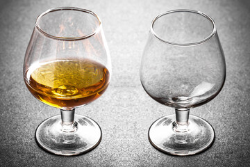 Brandy glass on rustic wood. Cognac alcohol background. Golden liquor closeup. Antique wooden plank...
