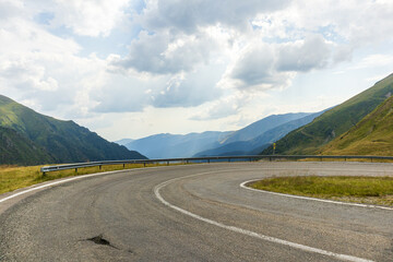 Fototapeta premium Mountain road in summer. Beautiful curved road, rocks, stones, blue sky with clouds. Landscape with empty highway through the mountain pass in summer. Travel