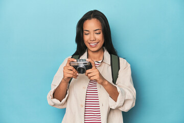 Young Filipina capturing moments with camera on a blue studio backdrop