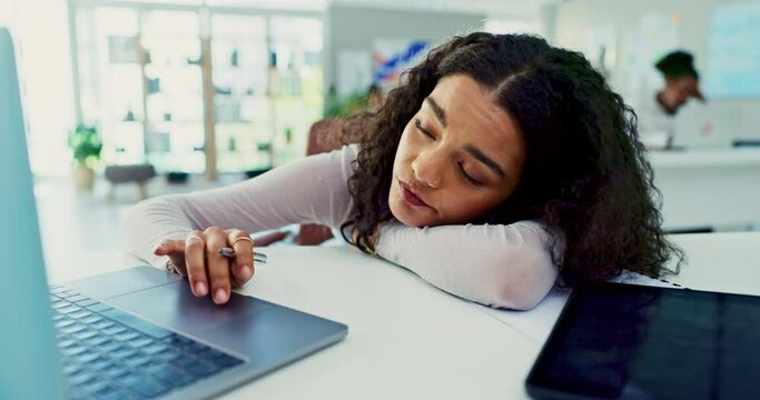 Laptop, burnout and bored with business woman lying on desk in office with fatigue or exhaustion from work. Computer, depression or tired and frustrated, unhappy or moody young employee in workplace