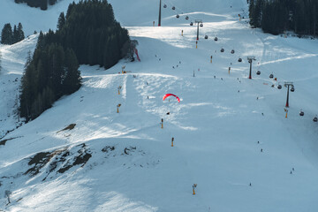 A paraglider flies over a snowy mountain landscape, enjoying the thrill of adventure and the beauty...