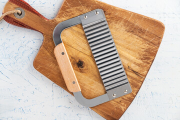 wavy knife lies on a wooden cutting board. View from above.