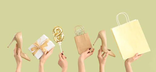 Female hands with shopping bags, gift and high heel shoes on green background. International...