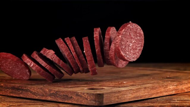 Pieces of salami fall onto a wooden board. Filmed on a high-speed camera at 1000 fps. High quality FullHD footage